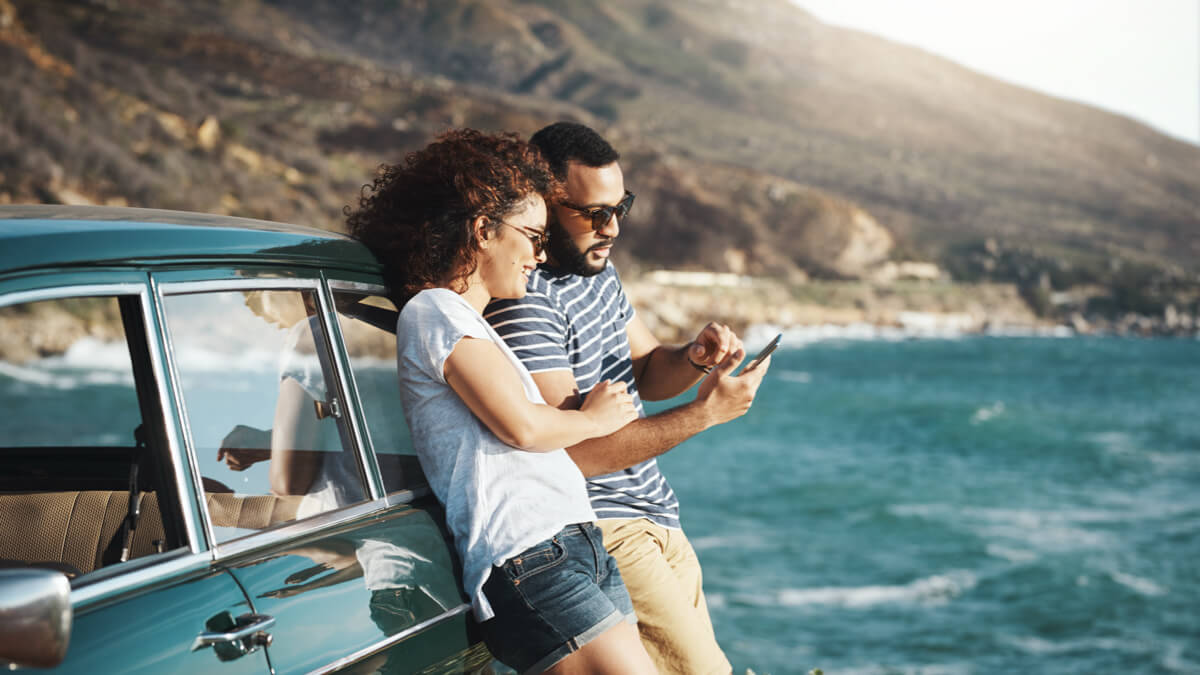 Shot of a young couple using a mobile phone on a road trip